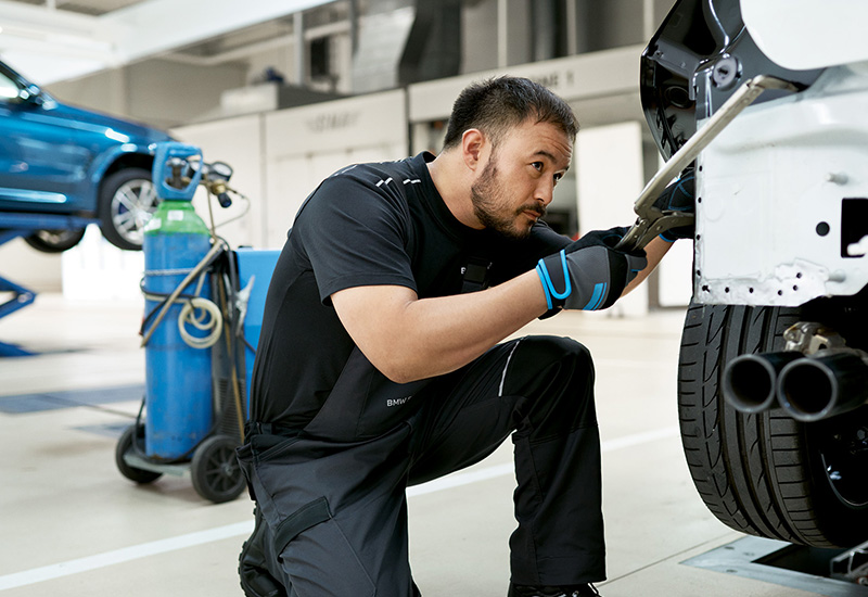 BMW Mechaniker bei Unfallinstandsetzung in der Werkstatt