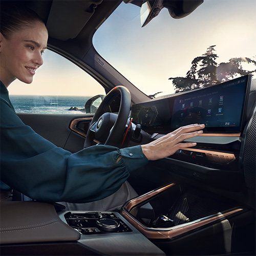 BMW X3 M50 xDrive Innenraum mit einer blonden Frau, die das BMW Curved Display bedient