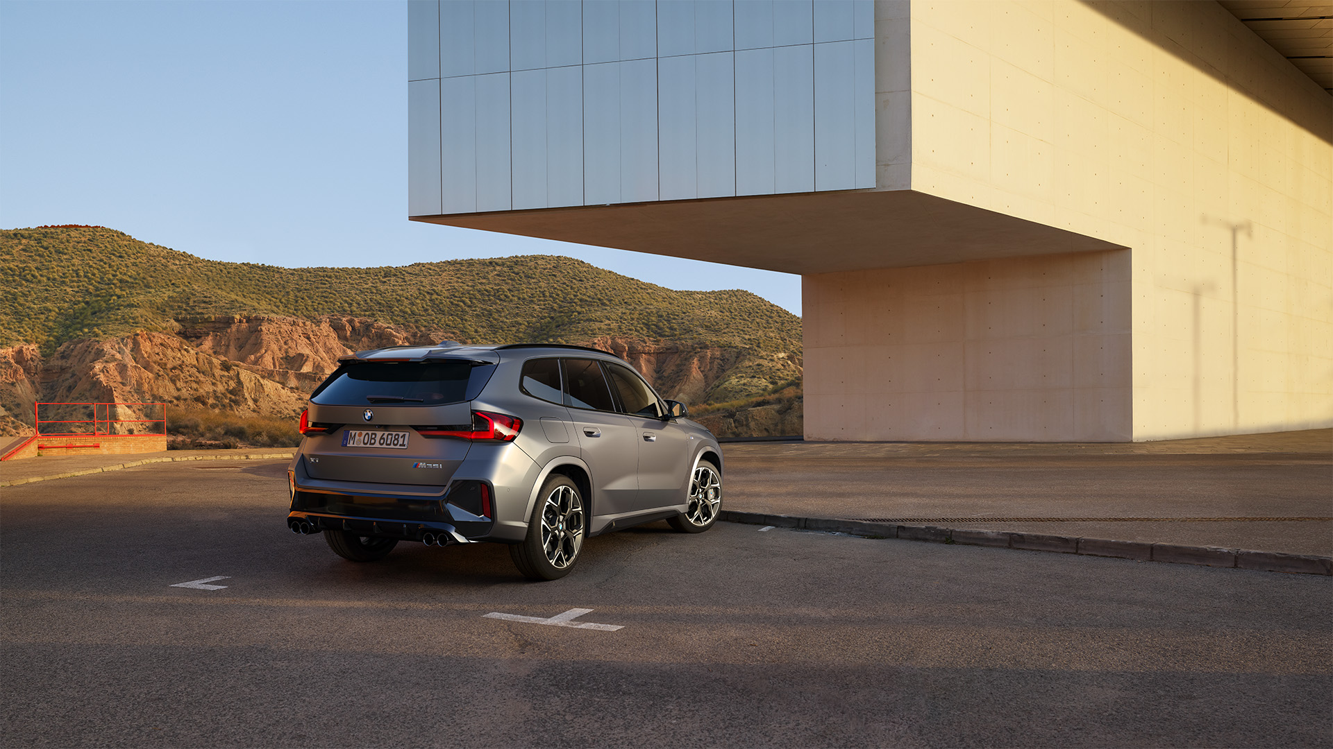 BMW X1 M35i Heckansicht fotografiert im Stand vor einem modernem Gebäude mit Vordach