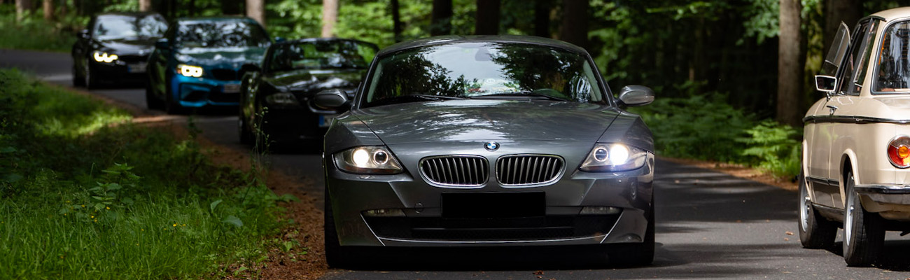 BMW Z4 Coupé Bj 2008, BMW Motion Spessart Rallye, weitere Teilnehmerfahrzeuge auf der Straße im Wald