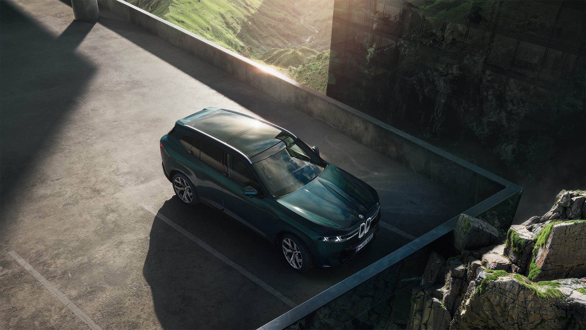 BMW X5 (G65) in Dunkelgrün stehend auf einem Parkdeck - fotografiert von oben mit Felsen im Hintergrund