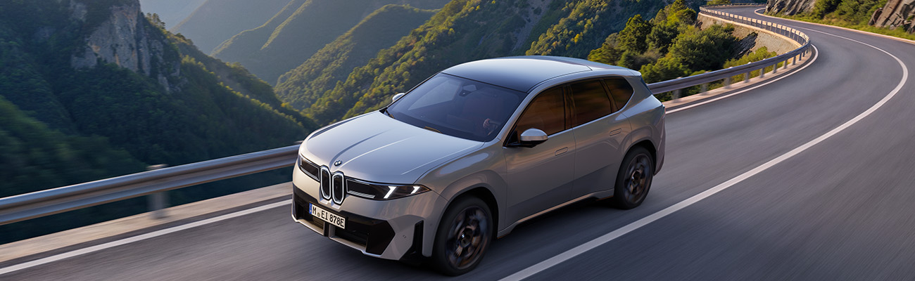 BMW iX3 bei der Fahrt auf Serpentinen-Straße durch alpines Gebirge
